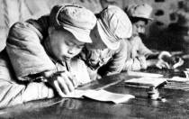 手把手教战友写字。1950年8月1日，中央军委发出《关于在军队中实施文化教育的指示》。